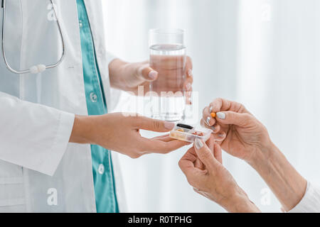 close up of young female doctor giving pills to senior woman Stock Photo