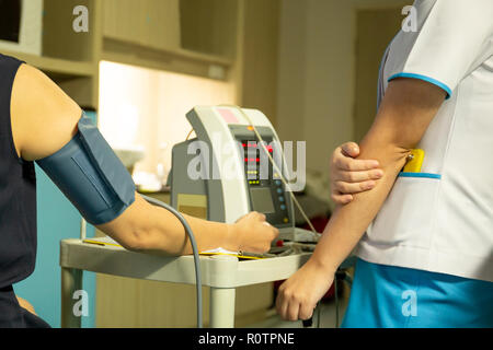Nurse checking blood pressure on monitor screen for patient health in hospital. Stock Photo