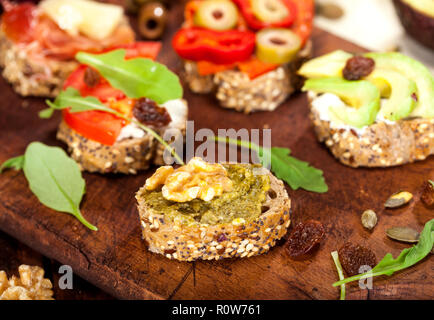 Closeup of different mini sandwiches on a cutting board and wooden table. Stock Photo