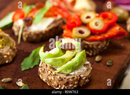 Closeup of different mini sandwiches on a cutting board and wooden table. Stock Photo