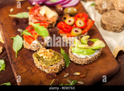 Closeup of different mini sandwiches on a cutting board and wooden table. Stock Photo