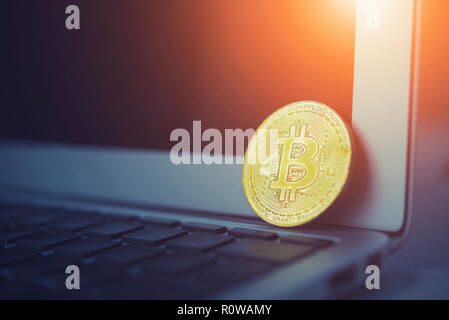 Bitcoin concept. Golden bitcoin put on laptop keyboard with empty screen with light. Picture for add text message. Backdrop for design art work.