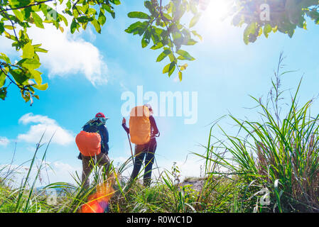 Travel background. Two backpacker standing on top of mountain looking forward to blue sky in sunny day. Freedom lifestyle. Fresh nature. Picture for a Stock Photo