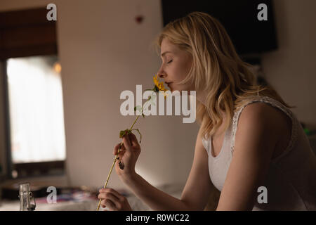 Woman smelling flower at home Stock Photo