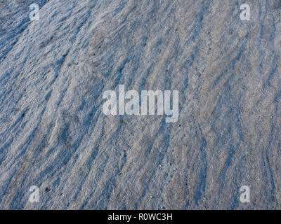 Close up of the rippled and weathered surface of a piece of grey rock. Stock Photo