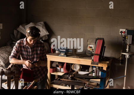 Female Metalsmith using mobile phone Stock Photo