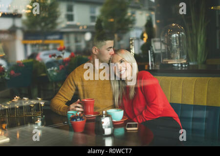 Man kissing woman forehead in cafe Stock Photo