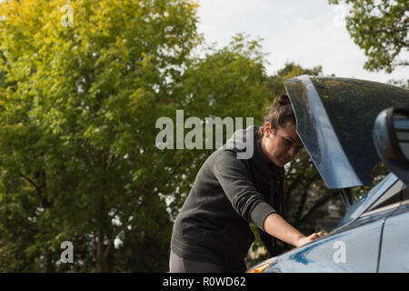 Woman checking a car during breakdown Stock Photo