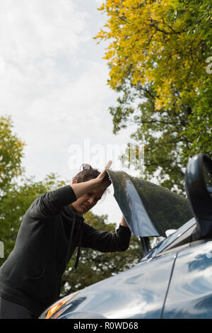 Woman checking a car during breakdown Stock Photo