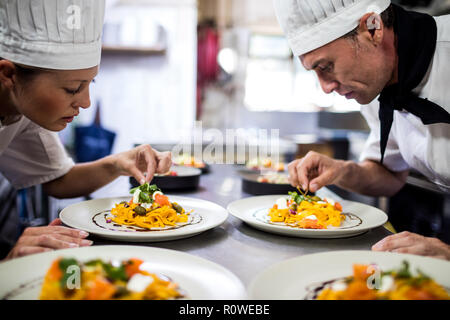 Chef garnishing food on plates Stock Photo