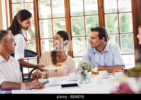 Waitress serving food in restaurant Stock Photo