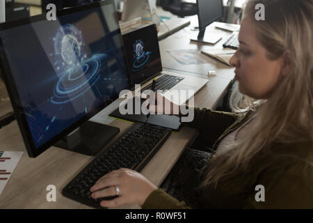 Executive using graphic tablet at desk Stock Photo