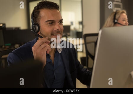 Customer service executive talking on headset at desk Stock Photo