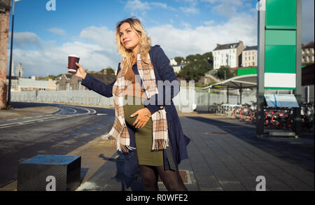 Pregnant woman waving at bus stop Stock Photo