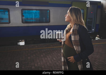 Pregnant woman having coffee on platform Stock Photo