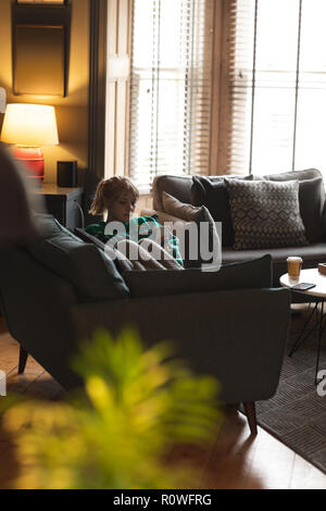 Woman using mobile phone on sofa in living room Stock Photo