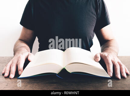 man reading book at wooden table Stock Photo
