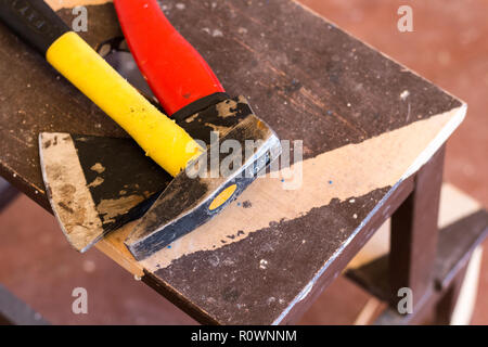 Building tools. Woodwork. Yellow hammer and red ax on a dark wooden background. Close up Stock Photo