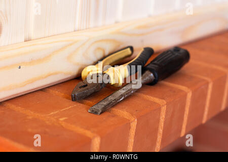 Building tools. Pliers and chisel on red brick. Close up Stock Photo
