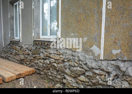 Collapsing base house. Old damaged wall of a saber house with a collapsing base of the house. Damaged foundation base house. Stock Photo