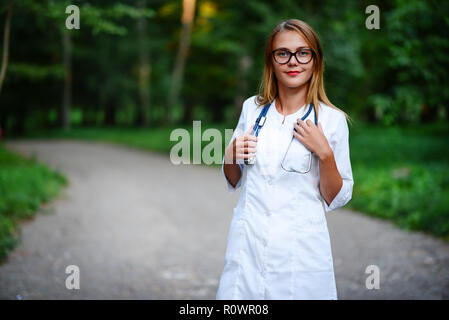 a young girl who is a doctor stands outside, she has crossed her arms on her chest. Stock Photo