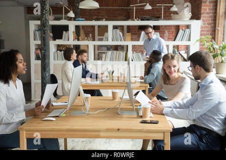 Multiracial employees working at computers together discussing p Stock Photo