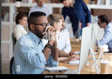 Black male worker talk on phone drinking coffee in office Stock Photo