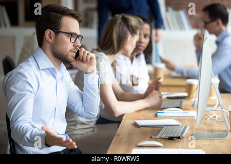 Angry male worker talk on phone solving business problems Stock Photo