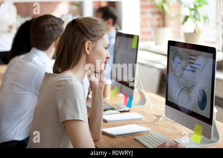Smiling female employee talking on phone while working at pc Stock Photo