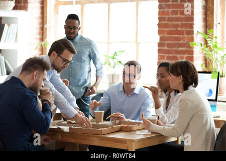 Diverse colleagues enjoy pizza having lunch break in office Stock Photo