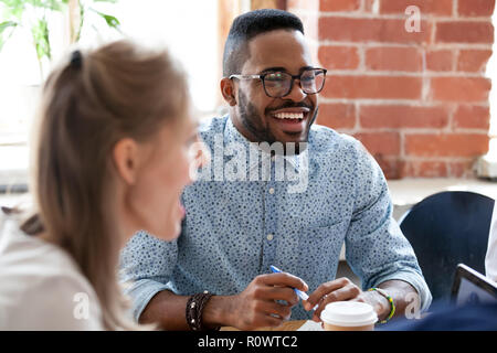 Diverse colleagues have fun laughing during casual office meetin Stock Photo
