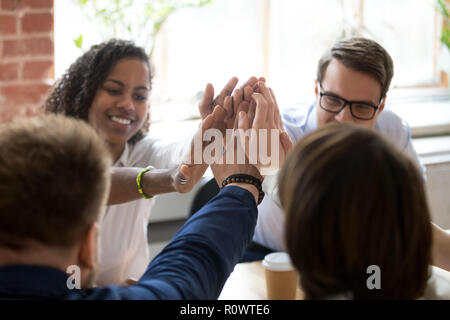 Diverse employees give high five during company office briefing Stock Photo