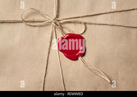 Rectangular recycled brown paper packaging tied with twine and sealed with red sealing wax. Stock Photo