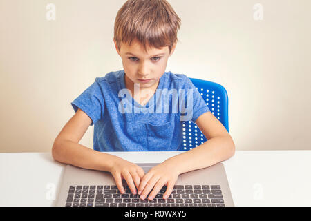 Concentrated boy typing on laptop computer Stock Photo