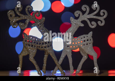 Two sparkling reindeer in white and gold with a bokeh background of red and white lights. Stock Photo