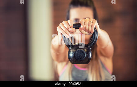 Attractive woman with slim body in gym holding a kettlebell. Stock Photo