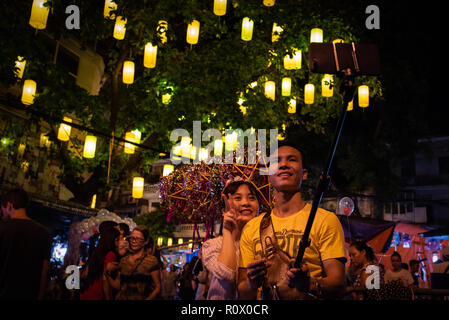 Vietnamese couple taking a selfie at night with lanterns overhead during the Mid-Autumn Festival, Hanoi, Vietnam. Stock Photo