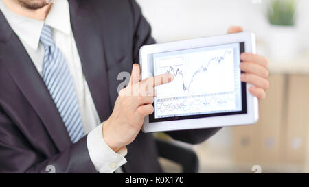 close up.Businessman pointing to a tablet with financial graph Stock Photo