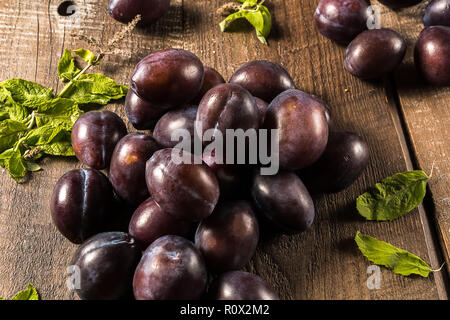 Flat lay view of ripe plums, on old wooden table background. Stock Photo