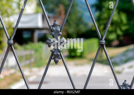 Decorative metal fence, behind which the house and the garden are visible blurred. Stock Photo