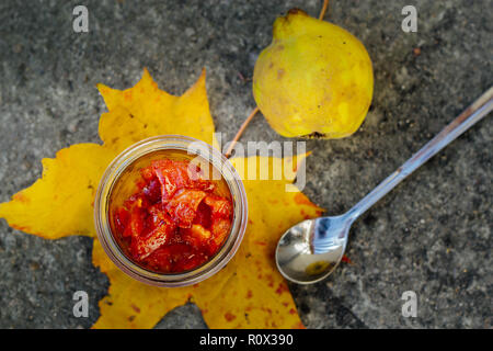 caramelized quince in a jar on a leaf, quince fruit and spoon Stock Photo