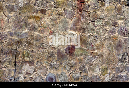 a piece of a flat stone wall, an old cracked surface consists of stones and rocks of various shades and structures, a variety of colors, old Stock Photo