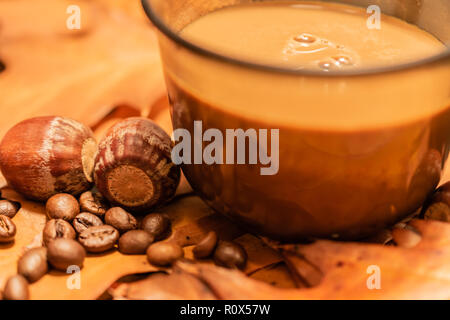 Coffee beans, a cup of coffee and two acorns on leaves during fall Stock Photo