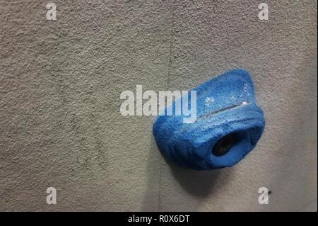 One blue rock climbing foothold against a grey wall Stock Photo