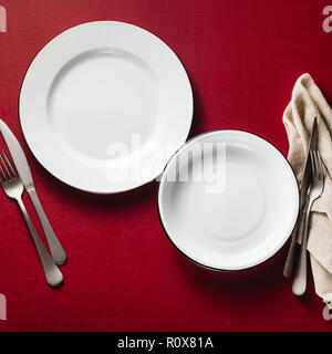 empty dining table set for two. two aluminum plates on a raspberry table with napkins and cutlery. copy space Stock Photo
