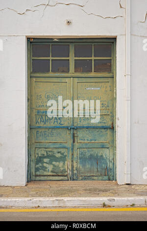 CRETE, GREECE - June 13, 2017: Abandoned house with wooden door. Dust words in greece written on dirty door. Stock Photo
