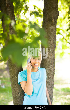 Portrait of sporty senior woman using mobile phone in the park Stock Photo