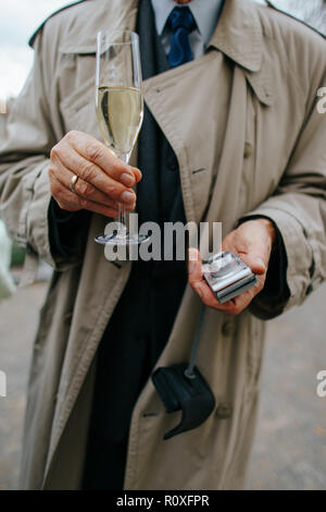 photo of Midsection of man holding a glass of champagne and a compact camera Stock Photo