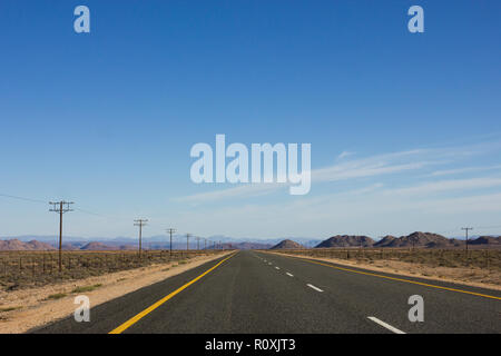 long empty tarred national road stretches out into the distance in a dry and arid landscape of South Africa on the Cape Namibia route Stock Photo