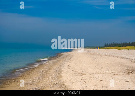 A tent far away on the white sandy beach with a lot of sea shells at the Baltic Sea on Fehmarn island in Germany on a nice vacation day with a blue... Stock Photo